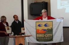 Charles Schwartz, State Coordinator of Bird City, presents Bird City flags to Madison and Maple Bluff. Photo from Madison Commons. 